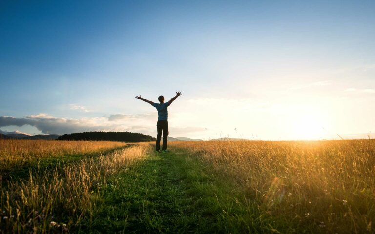 Man in a field with arms wide